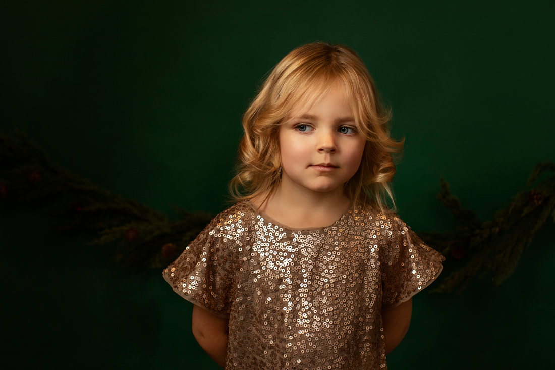 Photo of small girl in sparkling dress with dark green background. Gin Quist Photography