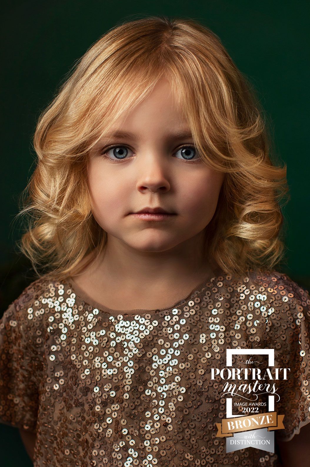 Photo of young blonde girl with curly hair and sparkly dress.