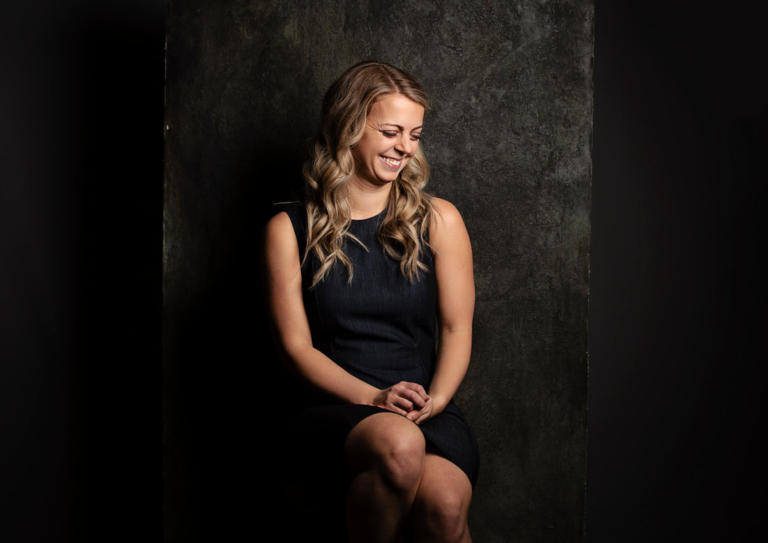 Photo of woman in studio in from of dark grey backdrop laughing. Edmonton Portrait Photographer